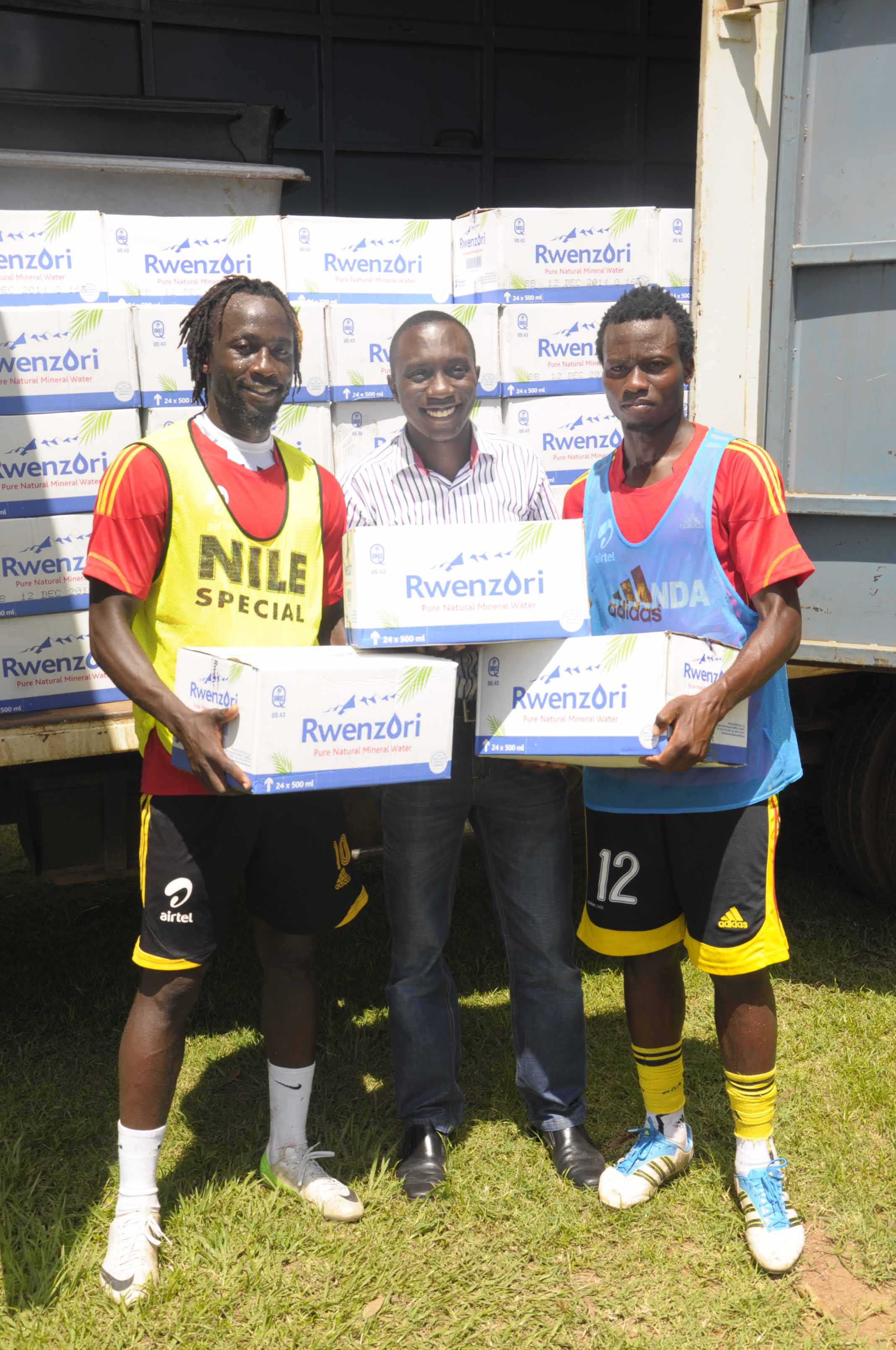 John Robert Katete, Rwenzori Brand Manager (centre) handing over water boxes to Cranes players Brian Umony (left) and Yunus Sentamu (right) at Lugogo.