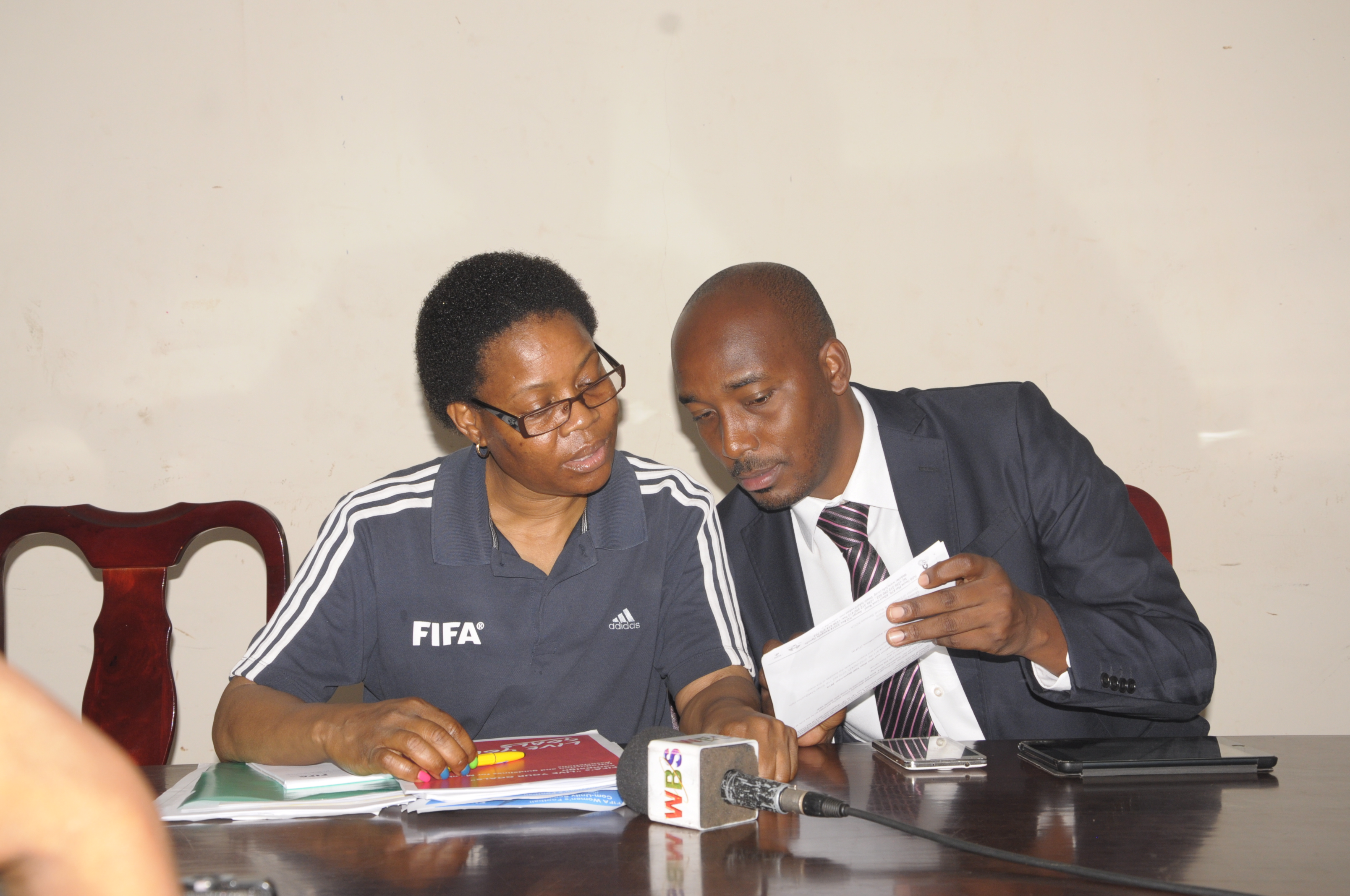 FIFA Development Officer Assistant-Administration and Projects Florie Ramogodi sharing notes with FUFA Communications Manager Ahmed Hussein during the weekly press conference.