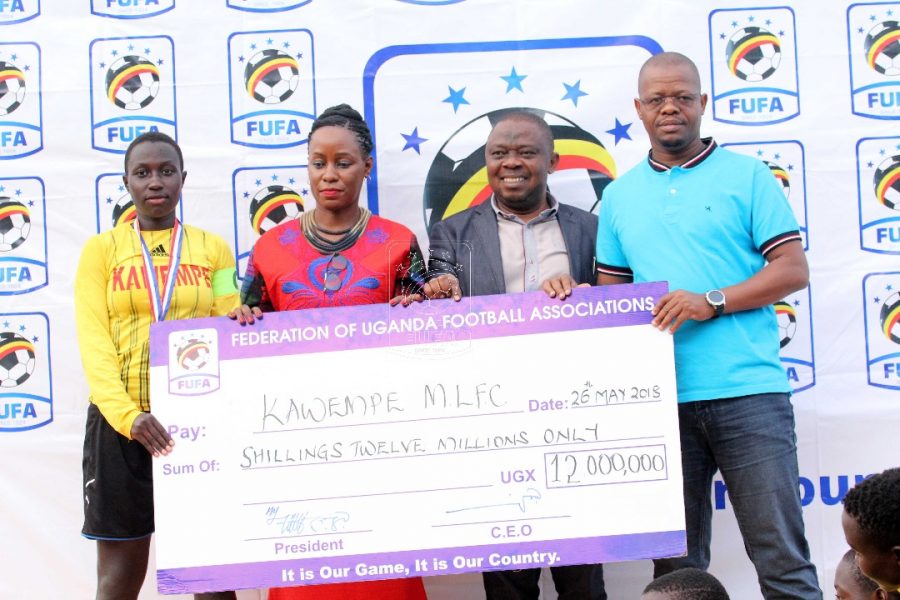 Kawempe Muslim Ladies FC Captain Nakabugo Mariam recieves a dame check from the FUFA President Eng. Moses Magogo (R)