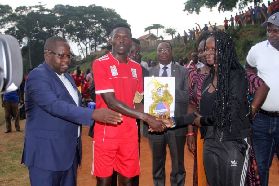 Bukedi's Ronald Musana recieves man of the match accolade and cash prize from Princess Ssangalyambogo as FUFA Drum Rogers Byamukama the FUFA Drum organising Committee chairman looks on